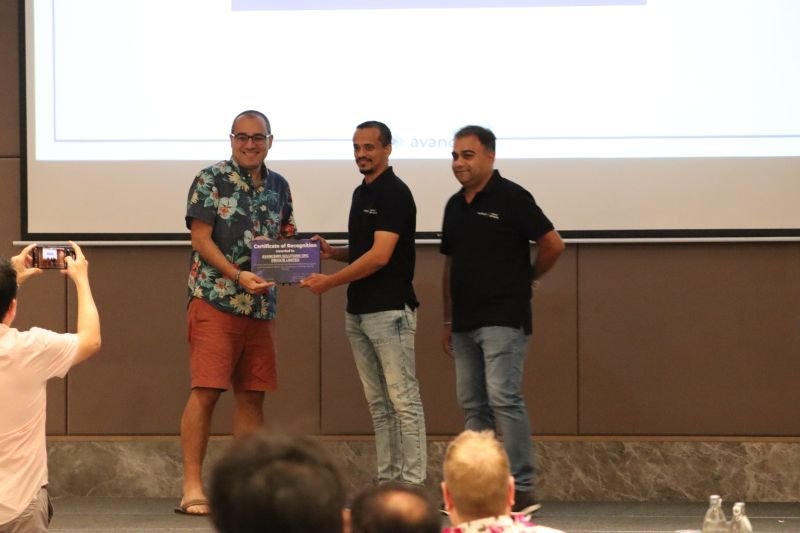 Two avancerPI colleagues accepting the Outstanding Service Partner certificate of recognition on stage
